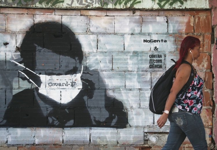 Una mujer camina delante de un graffity que burla al presidente, Jair Bolsonaro en Río de Janeiro (REUTERS/Sergio Moraes)