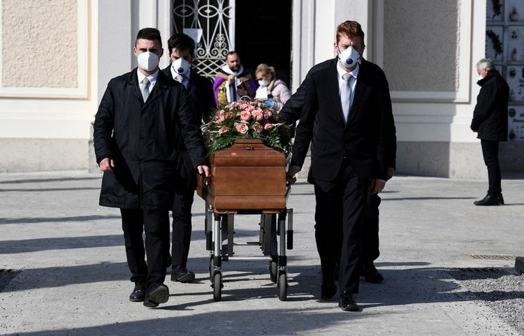 Portadores de féretros con máscaras protectoras llevan el ataúd de una mujer que murió de la enfermedad por coronavirus (COVID-19) en su funeral, en Seriate, Italia. 28 de marzo de 2020. REUTERS/Flavio Lo Scalzo
