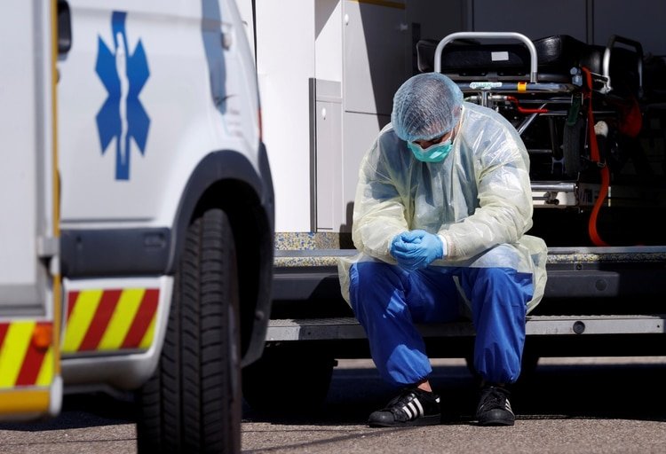 Un empleado sanitario descansa durante el traslado de pacientes de coronavirus a Alemania (Reuters)