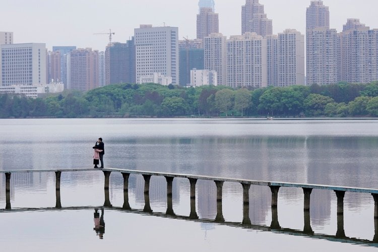 Una pareja con mascarillas de protección se abraza sobre un lago en Wuhan (Reuters)