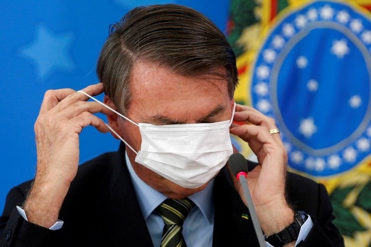 Jair Bolsonaro se ajusta su mascarilla protectora durante una conferencia de prensa en Brasilia, el 18 de marzo de 2020. (REUTERS/Adriano Machado/Foto de archivo)
