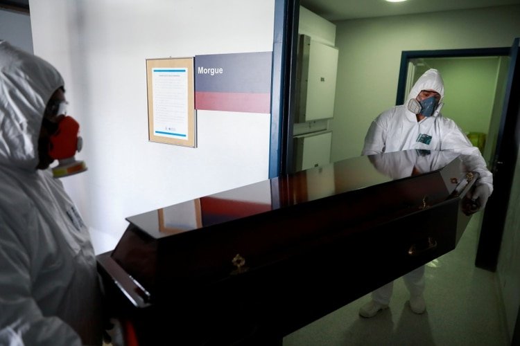 Trabajadores de una funeraria cargan el ataúd de una mujer de 83 años, que murió por razones desconocidas durante el brote de la enfermedad coronavirus (COVID-19), en Porto Alegre, Brasil, el 3 de abril de 2020. (REUTERS/Diego Vara)