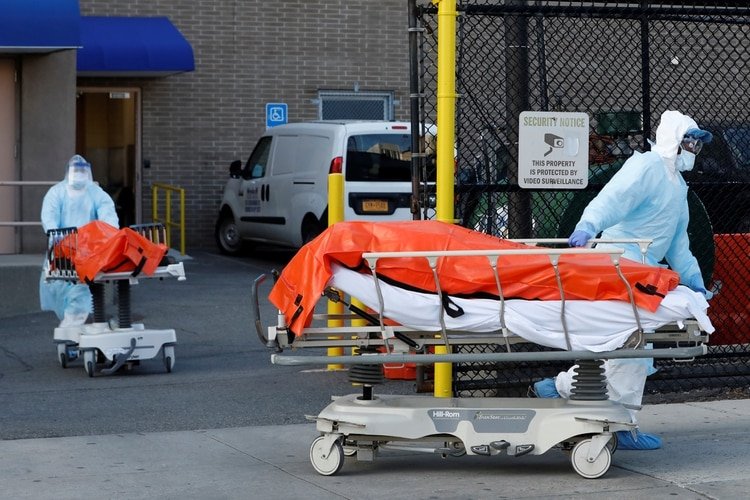 Trabajadores sanitarios de Nueva York transportan cuerpos de víctimas fatales de coronavirus. El estado es el la zona roja de la pandemia en los EEUU. (Reuters)