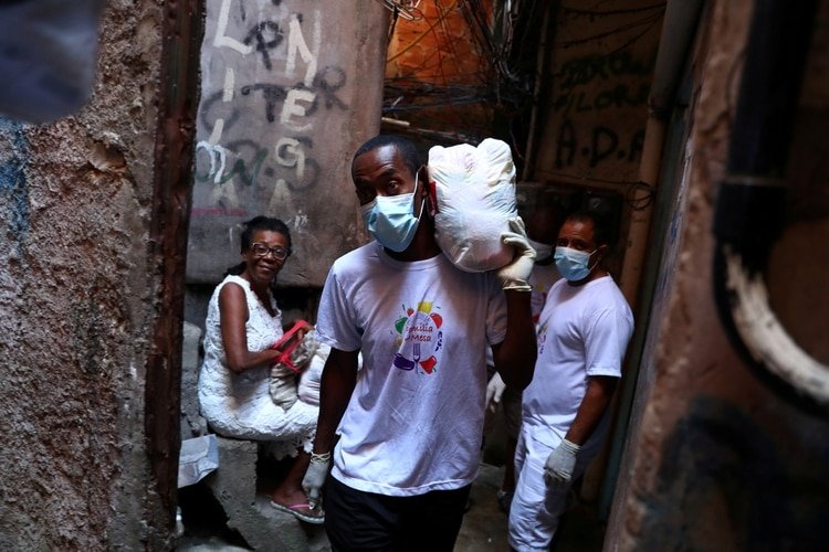 Un voluntario lleva comida a familias pobres de la Rocinha (REUTERS/Pilar Olivares/archivo)