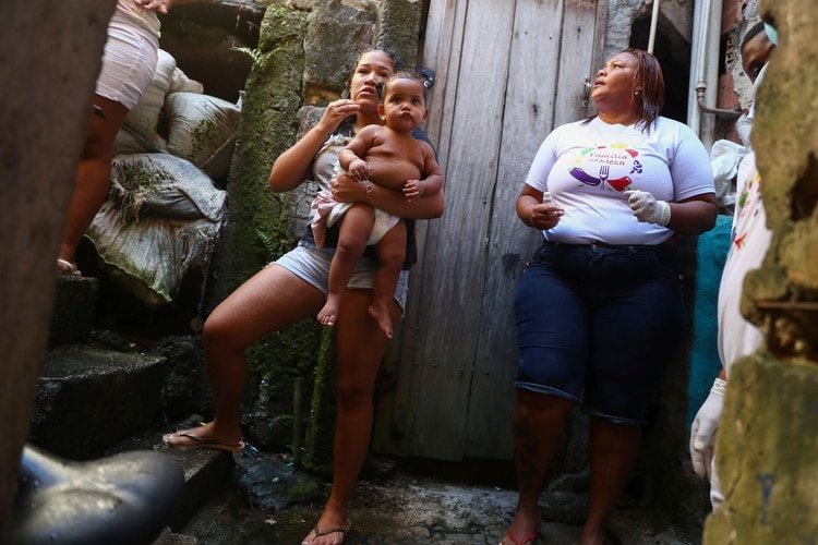 Una mujer con un bebé al lado de una voluntaria en la favela Rocinha (REUTERS/Pilar Olivares)