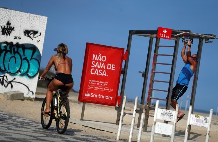 Una mujer que monta una bicicleta pasa un cartel que dice 