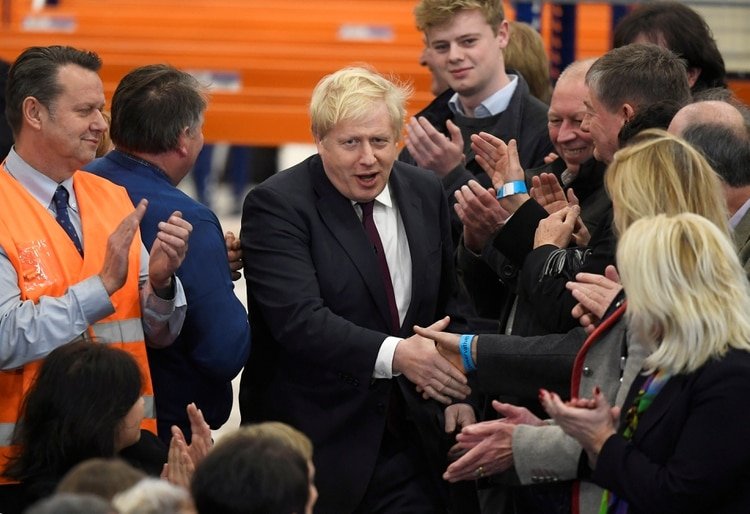 Johnson saluda a empleados durante una visita de campaña a una fábrica (REUTERS/Toby Melville)