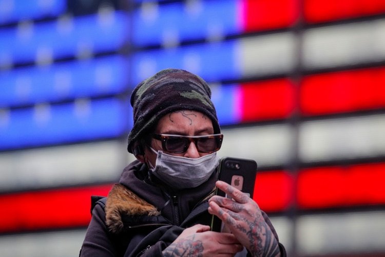 Un hombre con mascarilla mira su celular en Times Square (Reuters)
