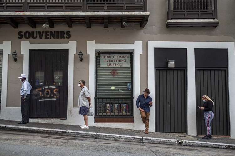 Personas se alinean a una distancia social prudente para ingresar a un supermercado que solo permite a cinco clientes a la vez en San Juan, Puerto Rico como consecuencia de la pandemia por coronavirus (AFP)