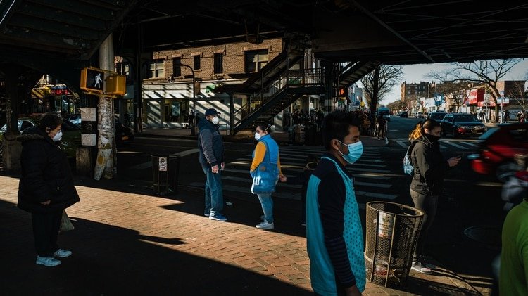 Transeúntes con cubrebocas en Jackson Heights, Queens, esperan para cruzar una intersección (Ryan Christopher Jones / The New York Times)