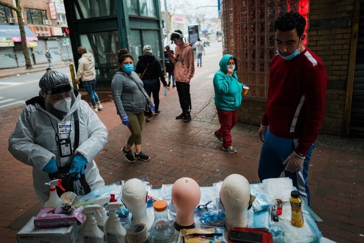 Vivien Grullon, a la izquierda, vende mascarillas, guantes y artículos de limpieza debajo de la estación del tren 7 en la avenida Roosevelt en Jackson Heights, Queens. (Ryan Christopher Jones / The New York Times)