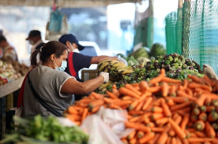 Una mujer que lleva una máscara protectora escoge verduras en un mercado callejero durante la cuarentena nacional en respuesta a la propagación de la enfermedad por coronavirus (COVID-19), en Caracas. 31 de marzo de 2020. REUTERS/Fausto Torrealba NO DISPONIBLE PARA REVENTA NI ARCHIVO.