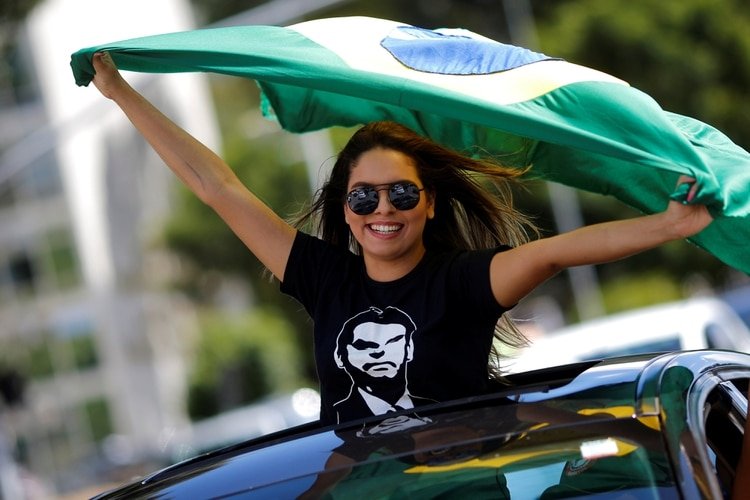 Una joven marcha con una bandera de Brasil y una remera con la cara de Bolsonaro (REUTERS/Adriano Machado)
