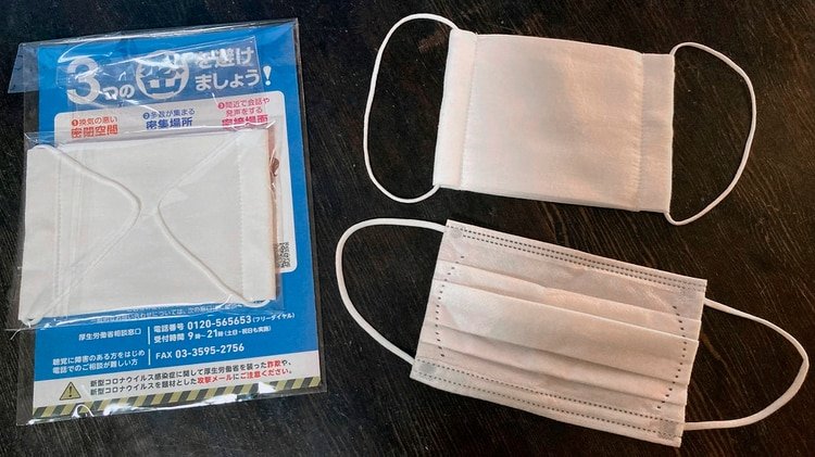 una de las mascarillas enviadas por el Gobierno (abajo, derecha.) comparada con otra de tipo quirúrgico (arriba, derecha.), el más usado entre los japoneses. (EFE/Antonio Hermosín) 