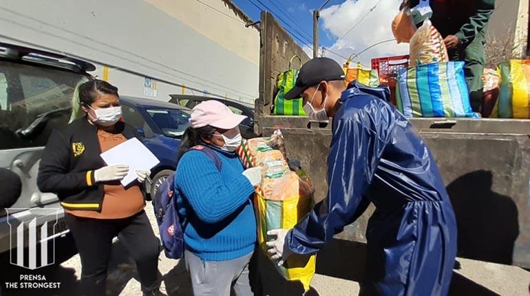 Jair Reinoso (der.) entrega una canasta a una de las beneficiarias, esta mañana. | Prensa Club The Strongest