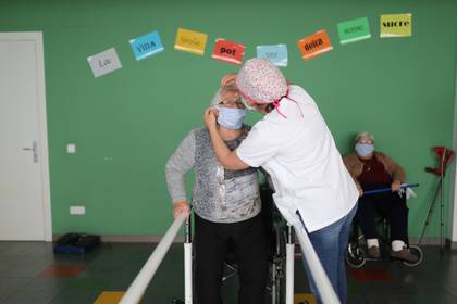Un trabajador social le pone una máscara protectora a una anciana en un asilo (REUTERS/Nacho Doce)