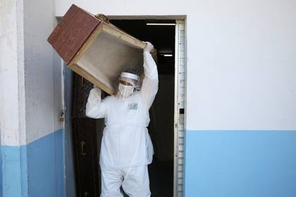 Un trabajador funerario de la ciudad de Manaos, utilizando vestimenta protectora, transporta un ataúd REUTERS/Bruno Kelly