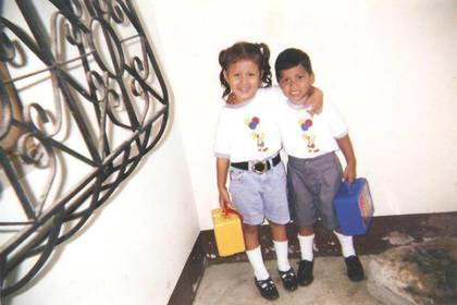 Paola y William de niños antes de su primer día de clases.