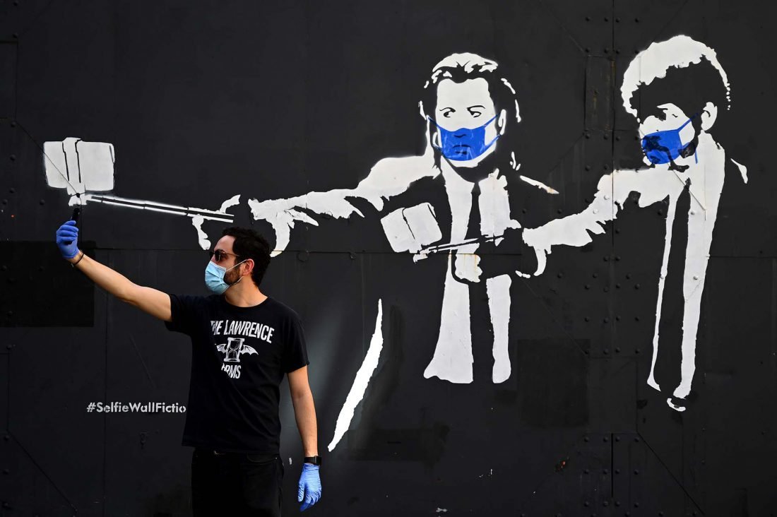 Un hombre se toma una selfie junto a un stencil de los actores Samuel L. Jackson y John Travolta en la películas 