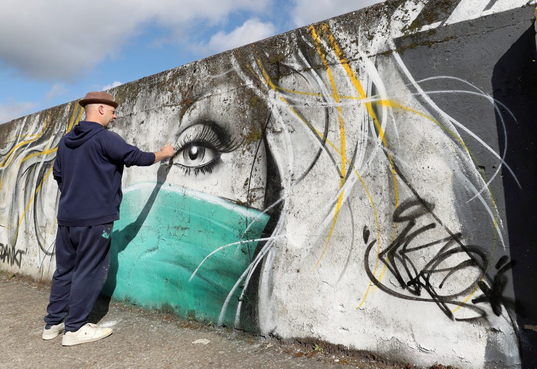 El artista belga CAZ retoca su mural en apoyo a los trabajadores de salud en Wetteren, Belgium.