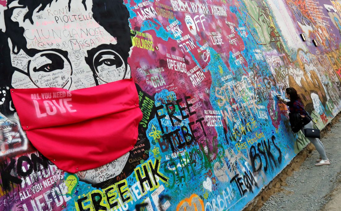 El legendario mural de John Lennon cubierto de graffitis en una calle de Praga, en la República Checa, fue adaptado a esta era de pandemia global.