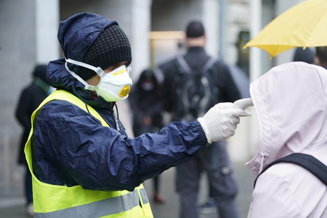 Un agente de seguridad toma la temperatura a cliente de la tienda de Apple en Berlín
