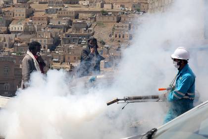 La gente se cubre el rostro mientras un trabajador de la salud fumiga una zona residencial durante una campaña de fumigación mientras continúa la propagación de la enfermedad coronavirus (COVID-19), en las afueras de Sanaa, Yemen, el 13 de abril de 2020. REUTERS/Khaled Abdullah
