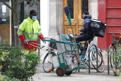 Un trabajador municipal y un repartidos de comida, en las afueras de París (Reuters)