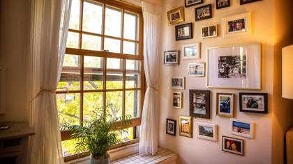 Fotografías familiares en un muro adyacente a la ventana de la sala de estar en la casa de Mara Gay