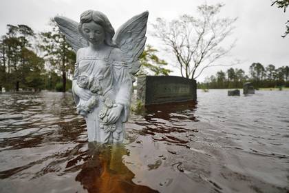FOTO DE ARCHIVO: Una estatua de un ángel está parcialmente sumergida por las aguas de la inundación en el cementerio de una iglesia donde los residentes se refugiaron y luego fueron evacuados, después del huracán Florence en Leland, Carolina del Norte, el 16 de septiembre de 2018. (REUTERS / Jonathan Drake / Foto de archivo)
