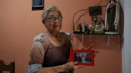 María Nunes Sinimbú muestra la foto de sus hijos fallecidos por coronavirus (Photo by Michael DANTAS / AFP)