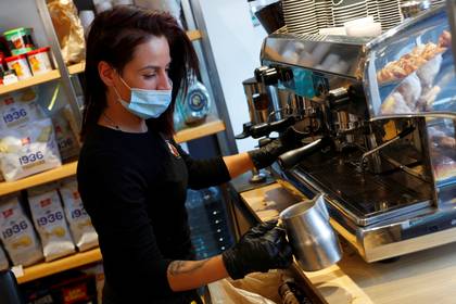 Una barista con un barbijo prepara un café en Trastevere, en Roma (REUTERS/Guglielmo Mangiapane)