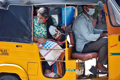 En India, una pasajera, su perro y el conducto de rickshaw utilizan barbijo. 