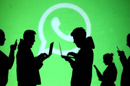 FILE PHOTO: Silhouettes of laptop and mobile device users are seen next to a screen projection of Whatsapp logo in this picture illustration taken March 28, 2018. REUTERS/Dado Ruvic/Illustration/File Photo