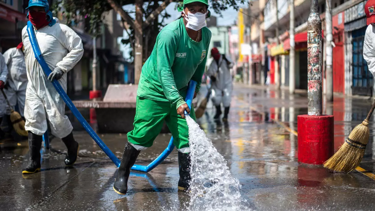 Trabajadores municipales limpian y desinfectan el entorno del mercado de Caqueta en el norte de Lima, el 30 de abril de 2020