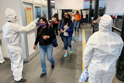 Usuarios del Metrobús pasan un filtro de seguridad y desinfección donde personal de Seguridad Pública, les toma la temperatura y les aplica gel antibacterial para poder ingresar a las instalaciones del sistema de transporte de Ciudad de México. EFE/José Pazos 