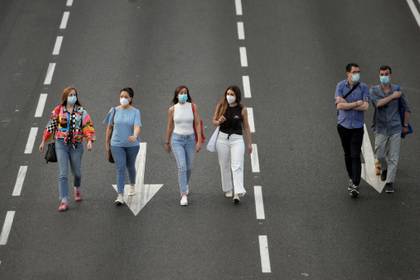 People wearing protective face masks walk along Paseo de la Castellana avenue amid the coronavirus disease (COVID-19) outbreak, in Madrid, Spain, May 30, 2020. REUTERS/Javier Barbancho