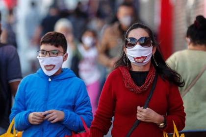Personas con tapabocas caminan frente a tiendas cerradas por la situación del coronavirus este viernes en la ciudad de Sao Paulo (Brasil). EFE/Sebastião Moreira