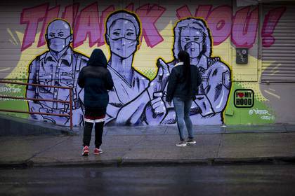 Dos mujeres frente a un mural del artista @Dister que muestra a los socorristas con máscaras y un mensaje de agradecimiento en el barrio de Harlem de Manhattan en la ciudad de Nueva York. 