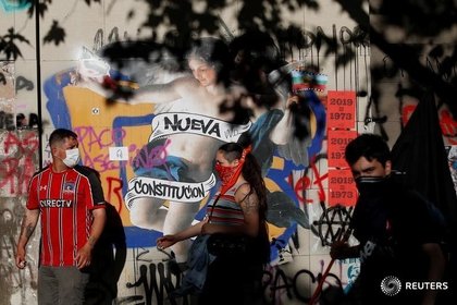 Foto de archivo. Manifestantes pasan frente a un graffiti pidiendo una "Nueva Constitución" en Santiago, Chile. November, 2019. REUTERS/Jorge Silva