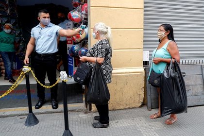 Un funcionario mide la temperatura de los clientes este miércoles en una tienda de la calle 25 de marzo, una de las regiones de comercio popular más importantes de Sao Paulo (Brasil). EFE/Sebastião Moreira 