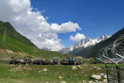 Soldados indios caminan junto a sus camiones estacionados en un campamento de tránsito improvisado antes de dirigirse a Ladakh, el 16 de junio de 2020 (REUTERS/Stringer)