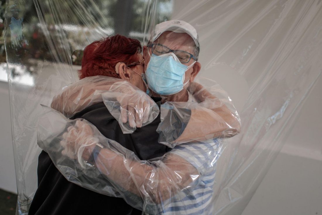 Una interna en una residencia de mayores en España abraza a su sobrino a través de un plástico.